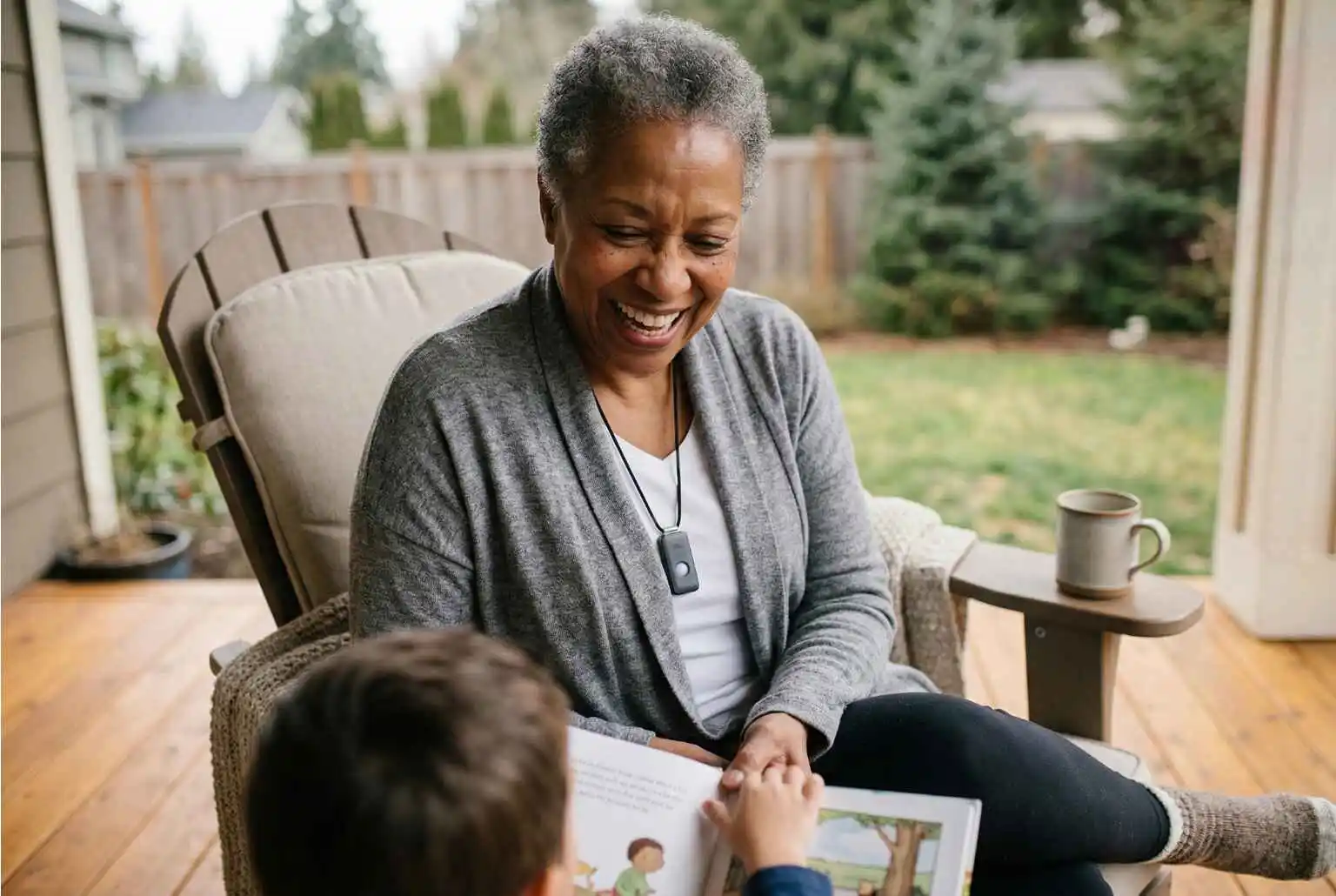 A grandmother reading with her grandchild on the patio while wearing her pendant